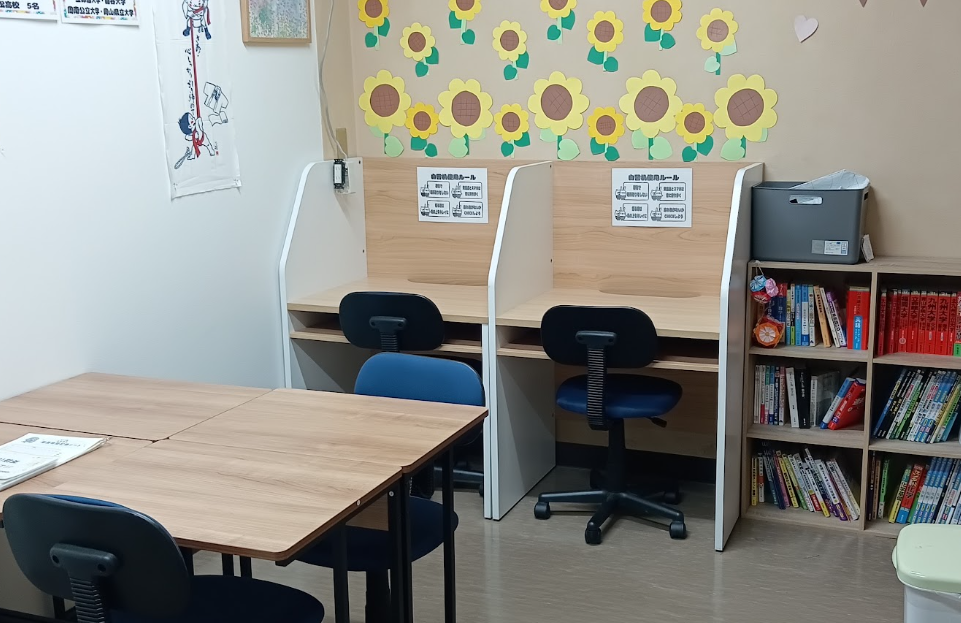 Two private study cubicles with wooden desks and blue chairs, sunflower wall decorations, and a bookcase on the right.